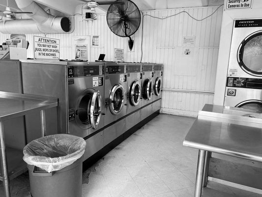 Washing machines and separate stacked dryers in a Miami laundromat, shown as an equipment example