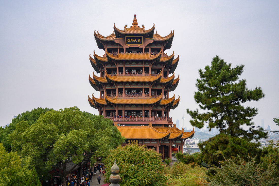 Yellow Crane Tower rising above trees with golden roofs and open balconies
